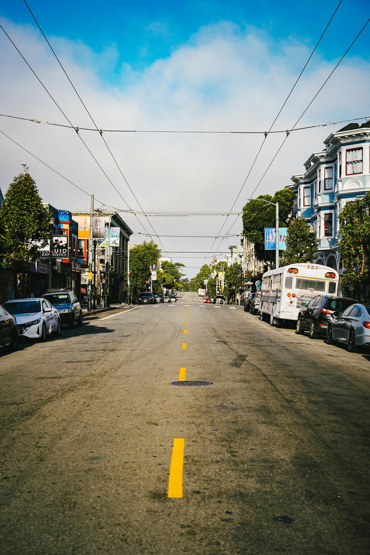 Haight Street view with Further tour bus parked in the distance under blue sky