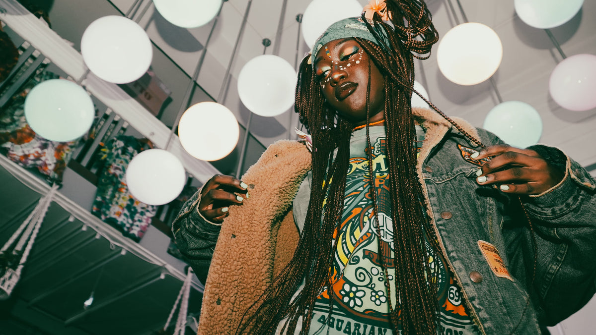 Woman dancing under globe lights in sherpa-lined denim jacket and psychedelic print top